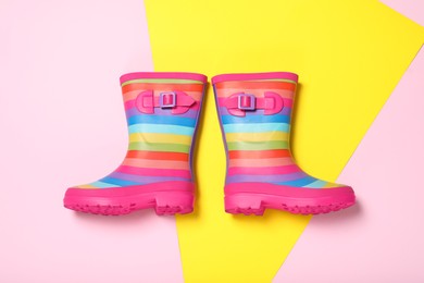 Photo of Pair of striped rubber boots on color background, top view