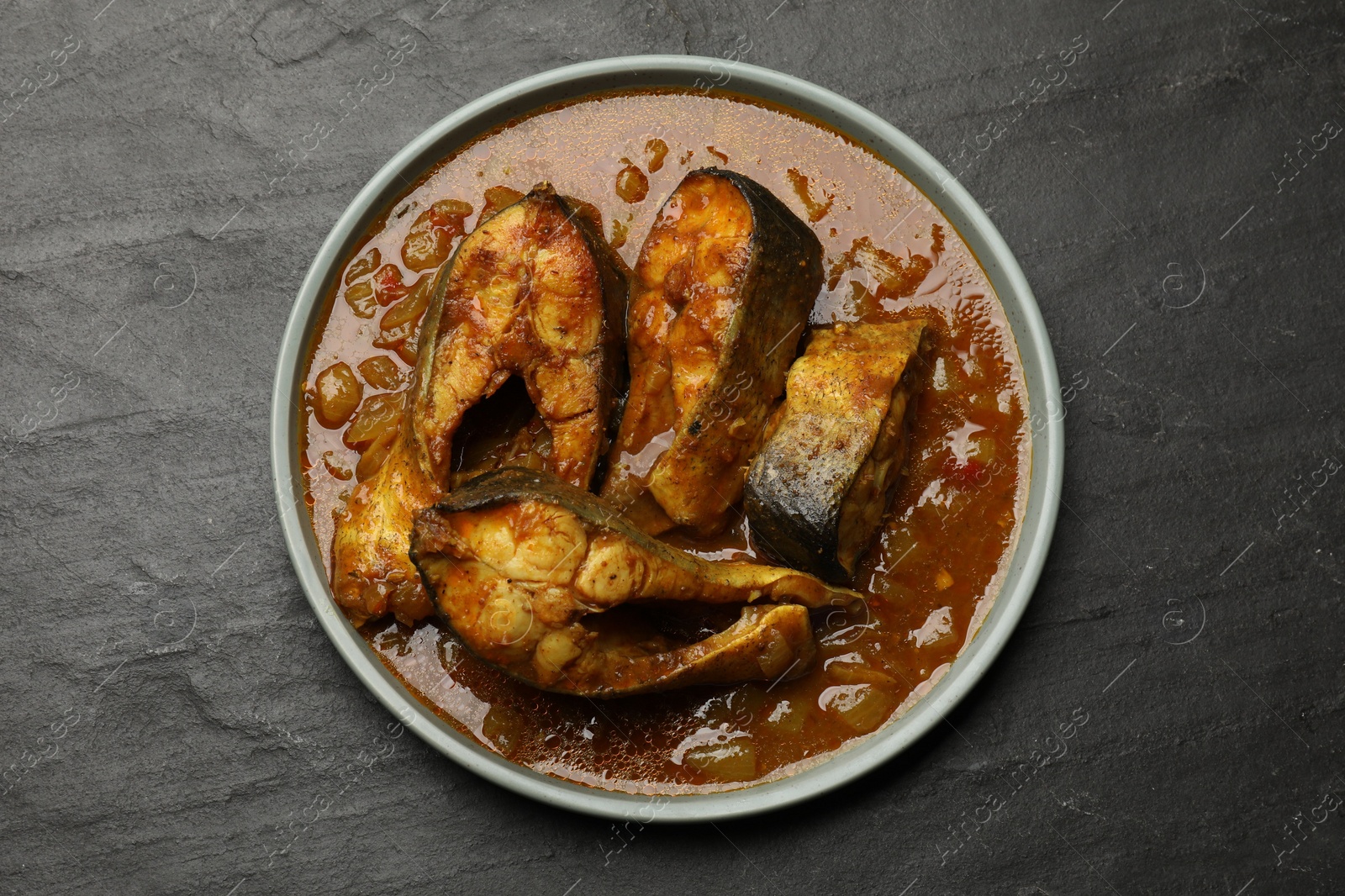 Photo of Tasty fish curry on grey textured table, top view. Indian cuisine