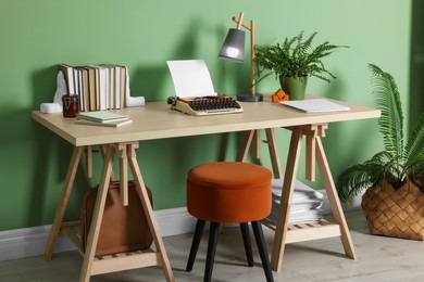 Photo of Writer's workplace with typewriter on wooden desk near pale green wall in room