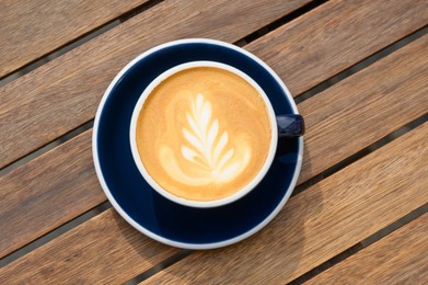 Cup of aromatic coffee on wooden table, top view