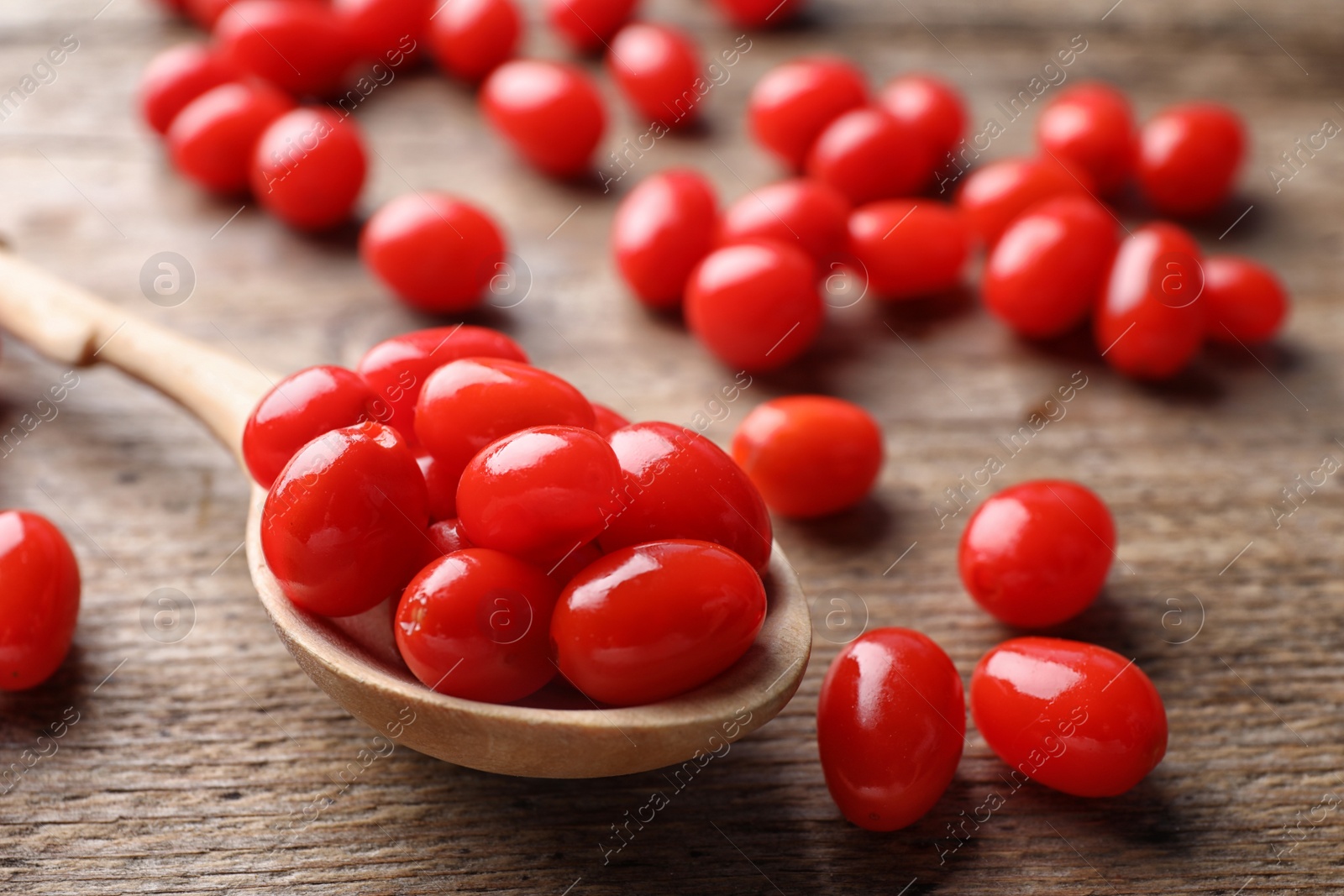 Photo of Fresh ripe goji berries and spoon on wooden table, closeup