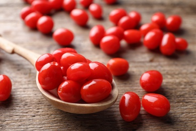 Fresh ripe goji berries and spoon on wooden table, closeup