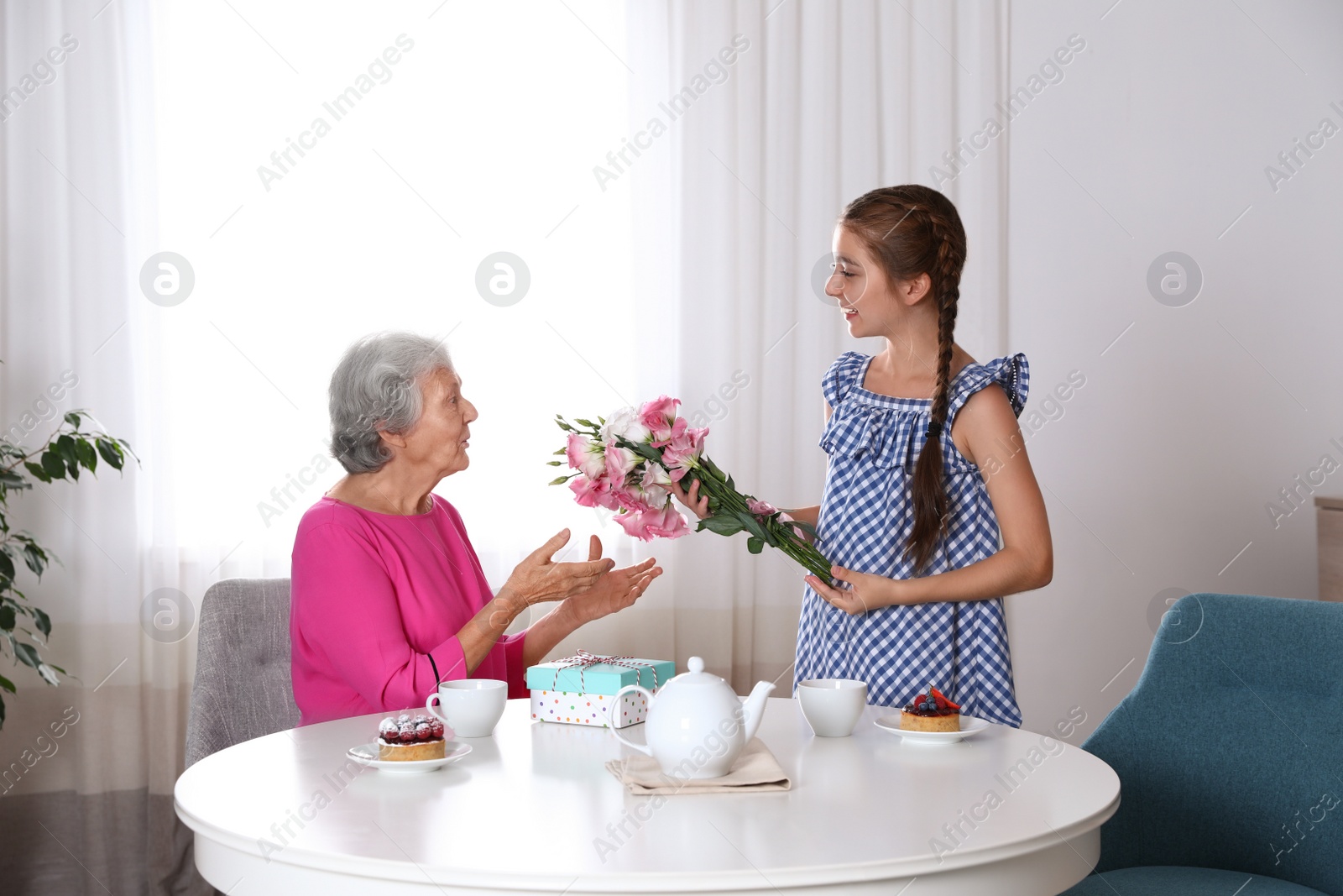 Photo of Preteen girl congratulating her granny at home. Happy Mother's Day