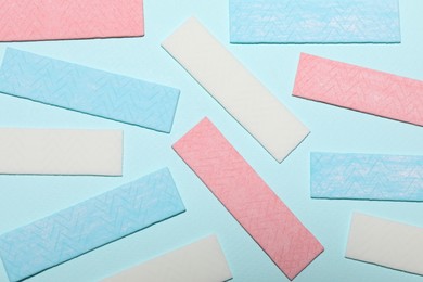 Sticks of tasty chewing gum on light blue background, flat lay