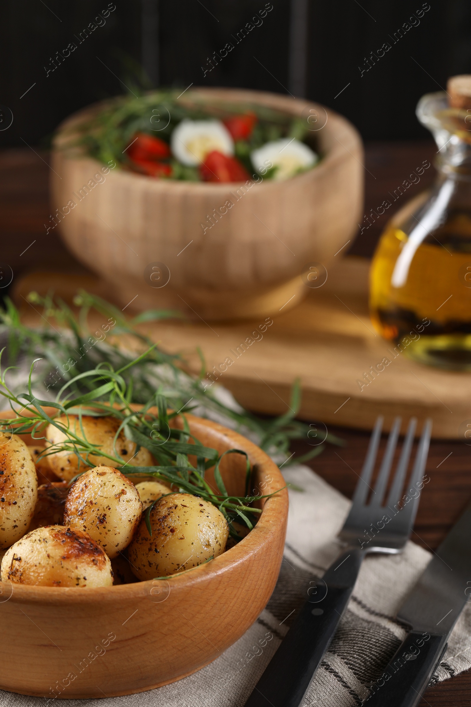 Photo of Delicious grilled potatoes with tarragon and salad on table, selective focus