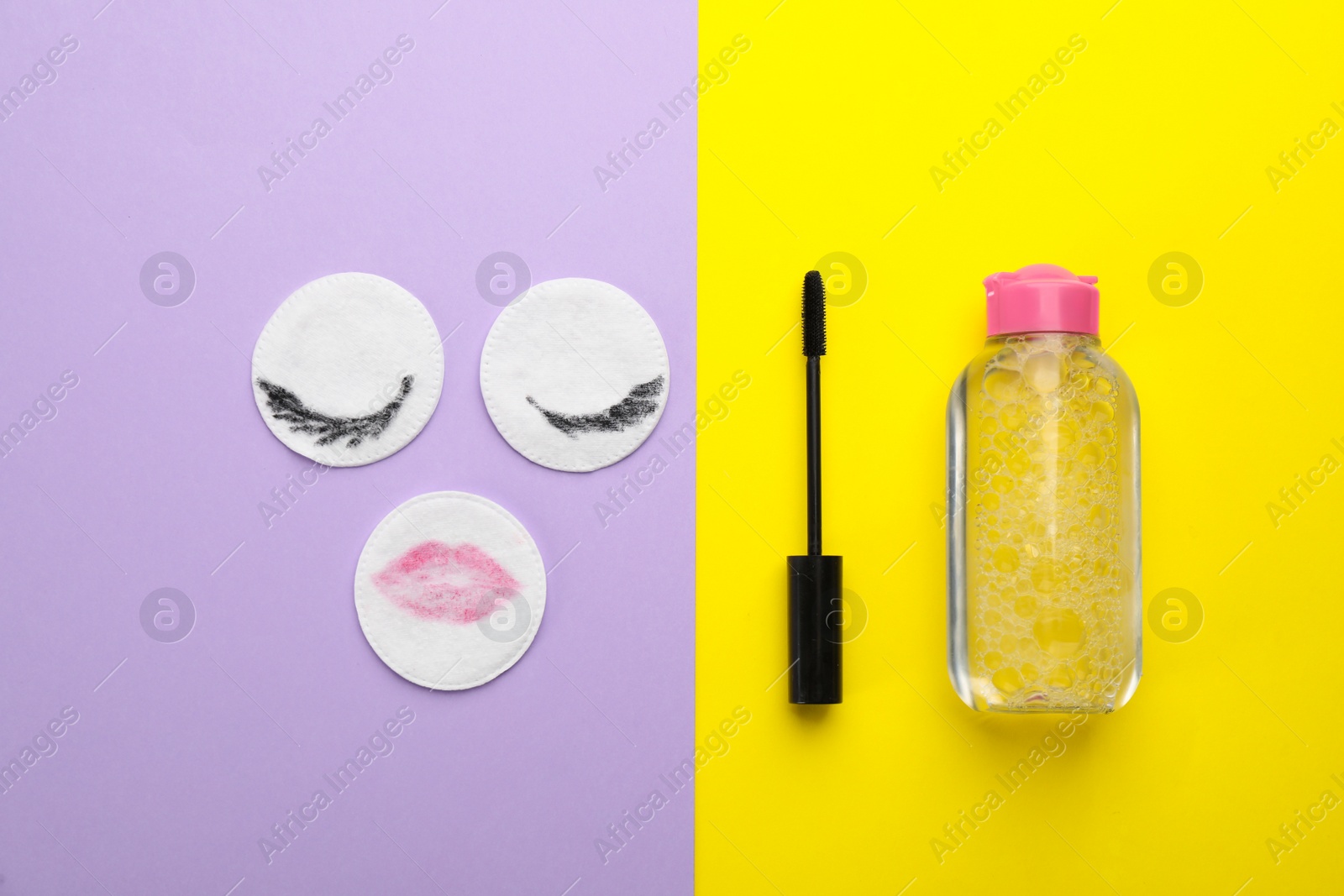 Photo of Dirty cotton pads, mascara and micellar cleansing water on color background, flat lay