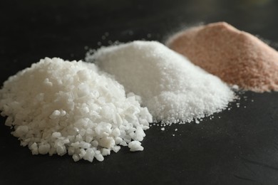 Photo of Different types of organic salt on black table, closeup