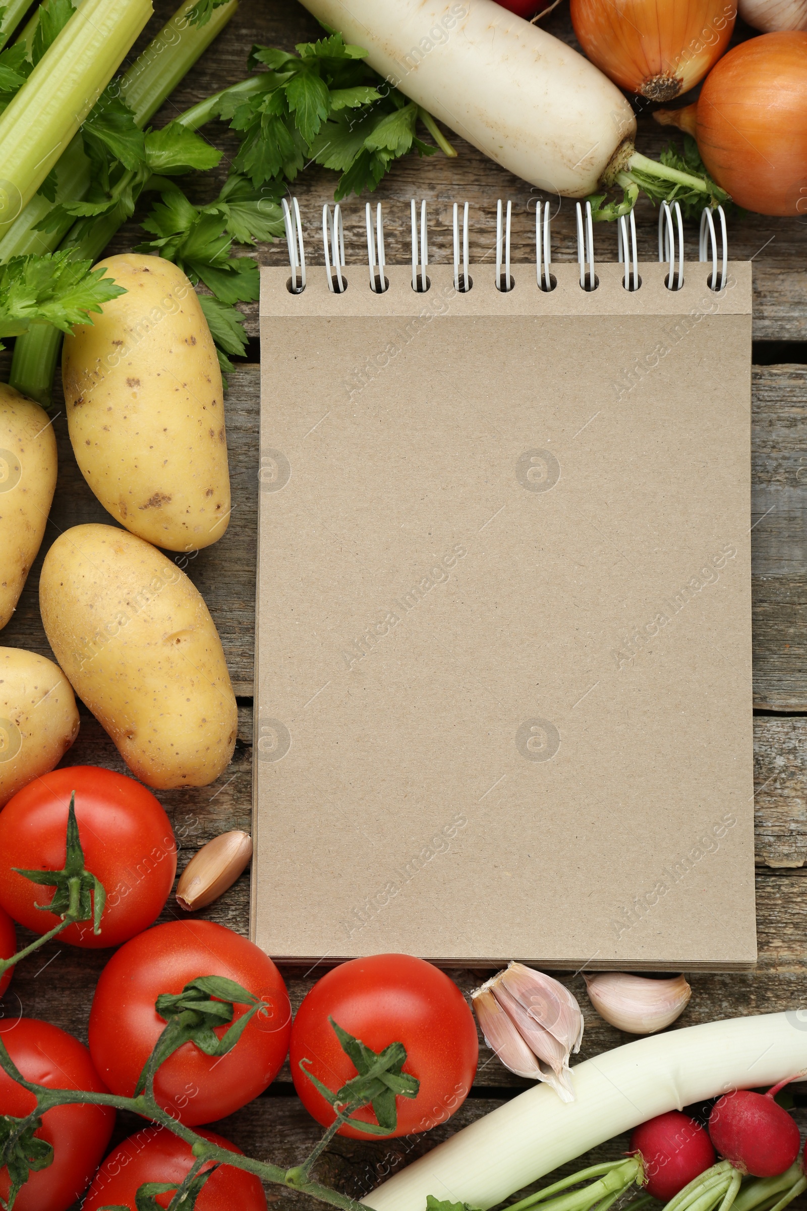 Photo of Blank recipe book and different ingredients on wooden table, flat lay. Space for text