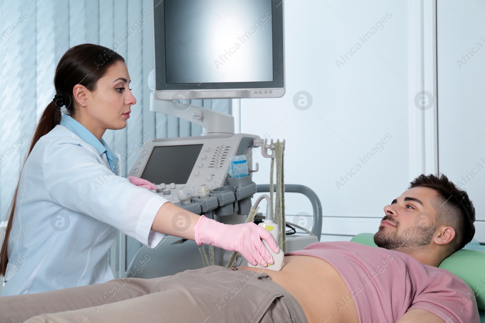 Photo of Doctor conducting ultrasound examination of patient's abdomen in clinic