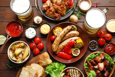Photo of Delicious meal served for barbecue party on wooden table, flat lay