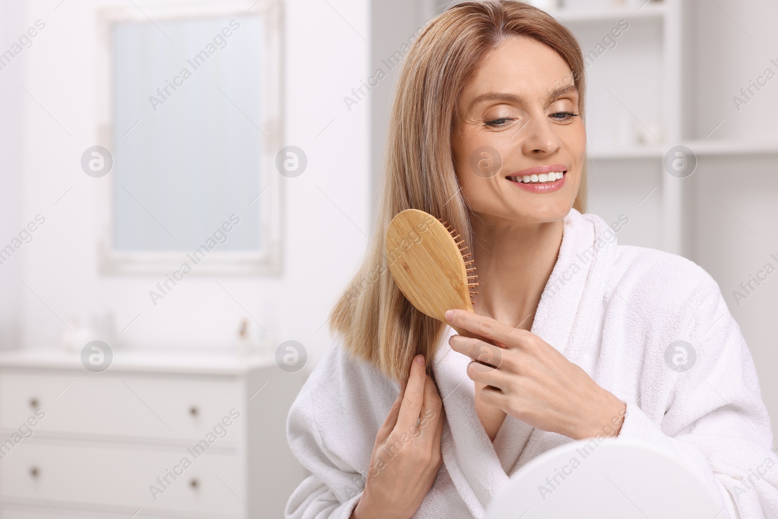 Photo of Beautiful woman brushing her hair in room