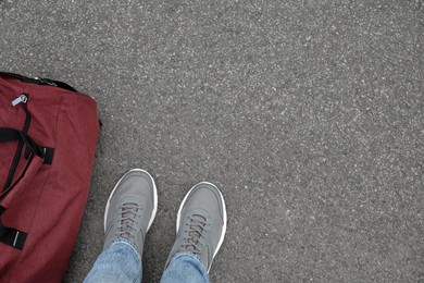 Photo of Man with bag standing on asphalt, top view. Space for text