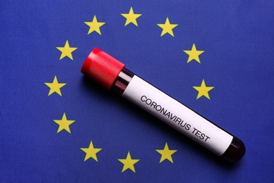 Photo of Test tube with blood sample on European Union flag background, top view. Coronavirus outbreak