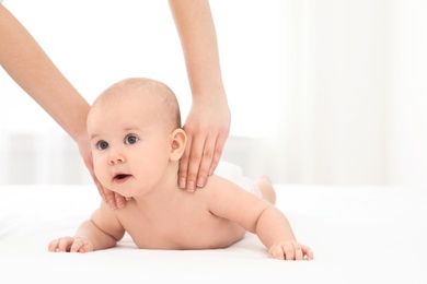 Mother and her cute child on bed indoors, space for text. Baby massage and exercises