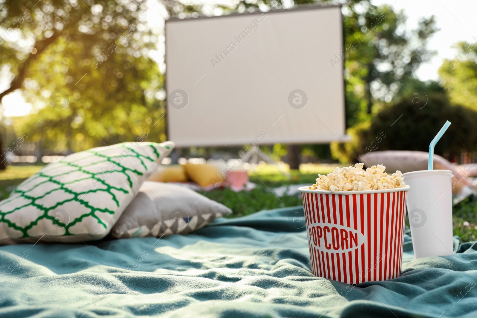 Photo of Popcorn and drink on blanket in open air cinema. Space for text