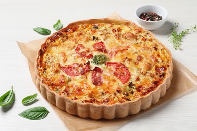 Photo of Tasty quiche with cheese, tomatoes and basil leaves on white wooden table