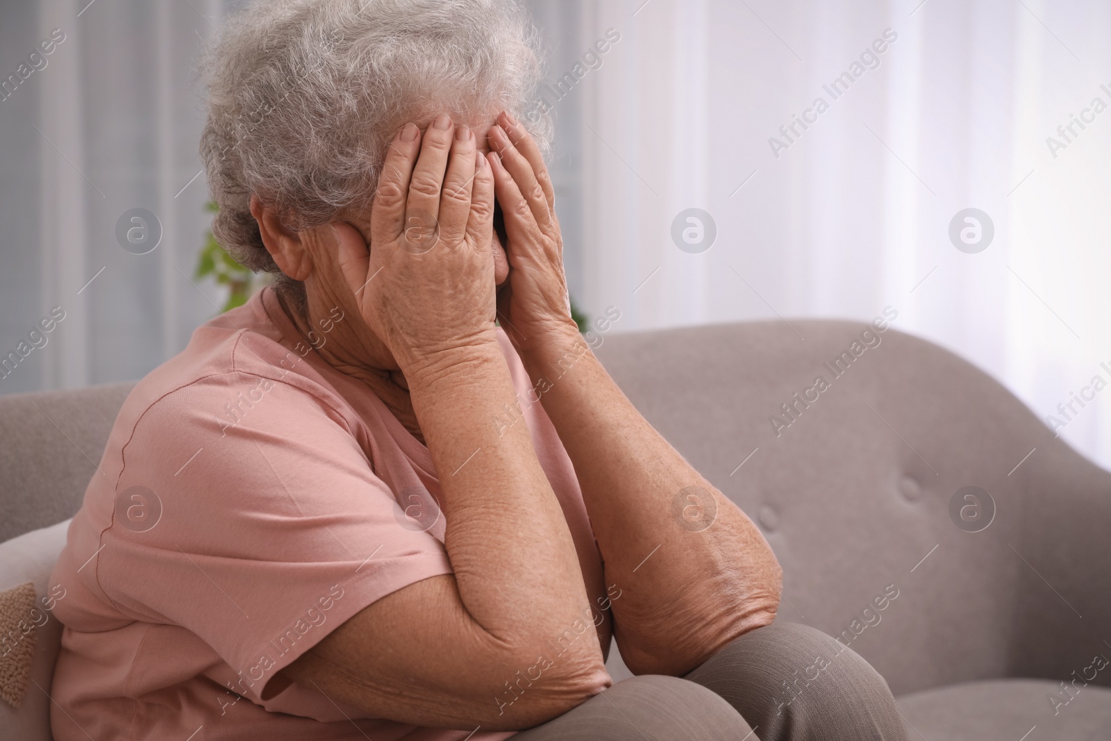 Photo of Senior woman with headache sitting on sofa at home