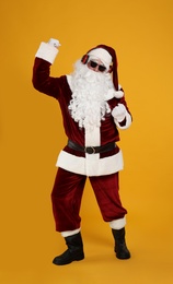 Santa Claus with headphones listening to Christmas music on yellow background