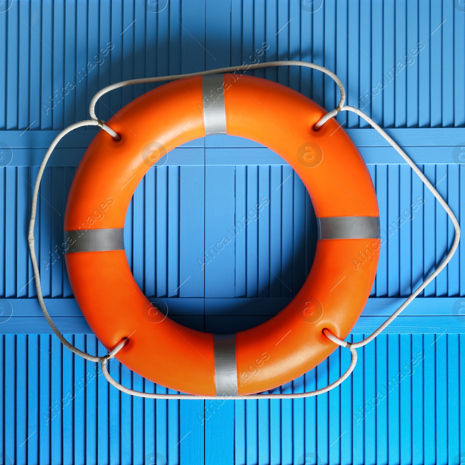 Photo of Orange lifebuoy on blue wooden background. Rescue equipment