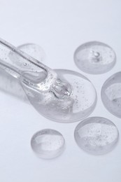 Photo of Pipette with samples of cosmetic serum on white background, closeup