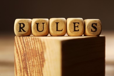 Photo of Word Rules made of cubes with letters on wooden block, closeup