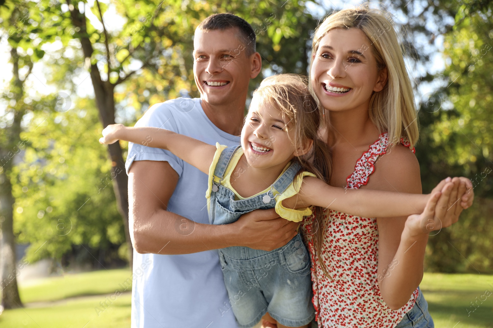 Photo of Happy parents with their child having fun outdoors. Spending time in nature