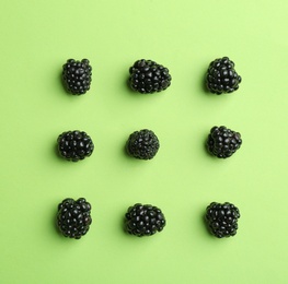 Fresh ripe blackberries on green background, flat lay