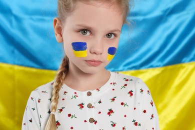 Little girl with face paint near Ukrainian flag