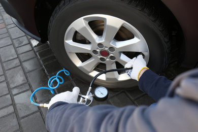 Mechanic checking tire air pressure at car service, closeup