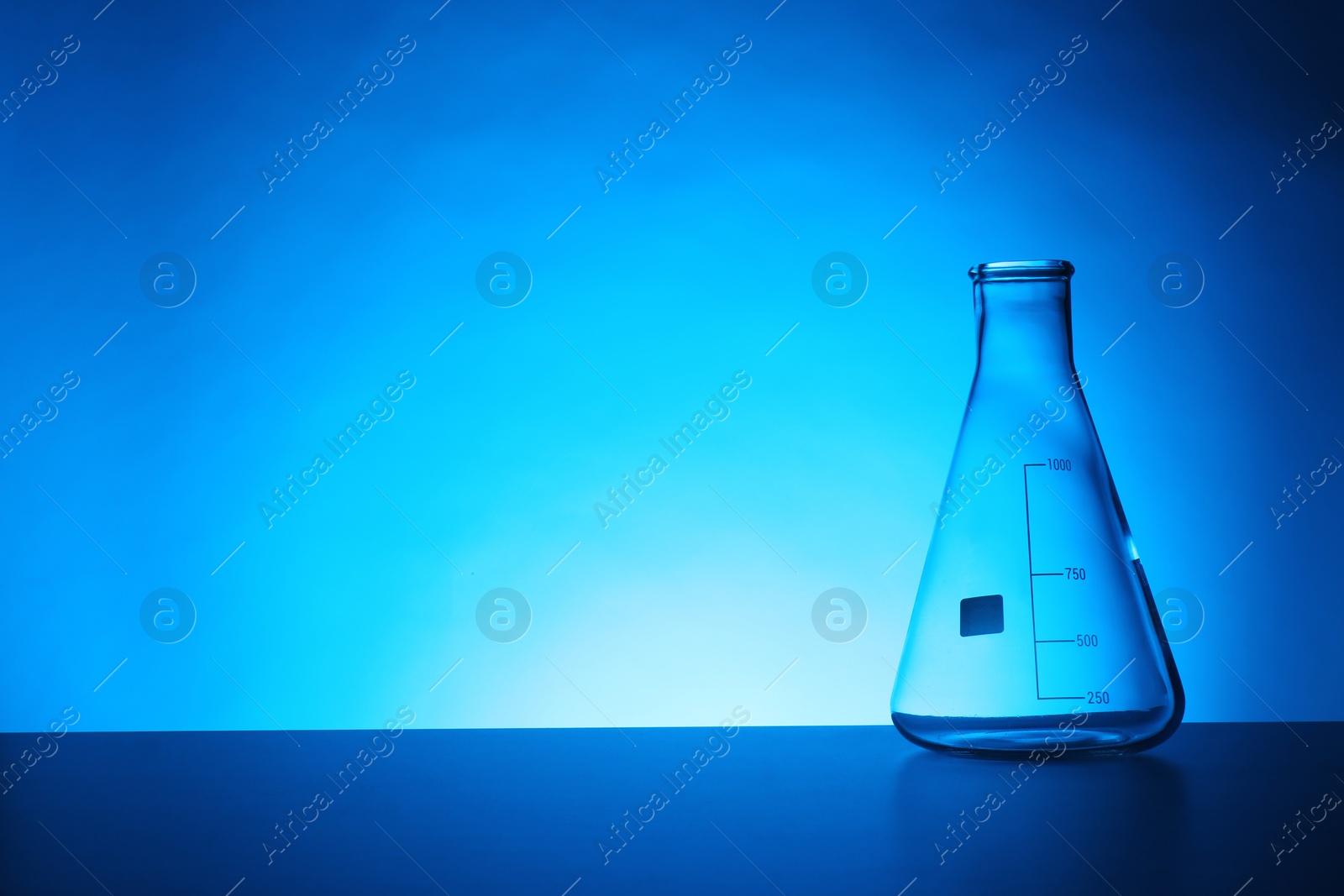 Photo of Empty conical flask on table against color background. Chemistry laboratory glassware