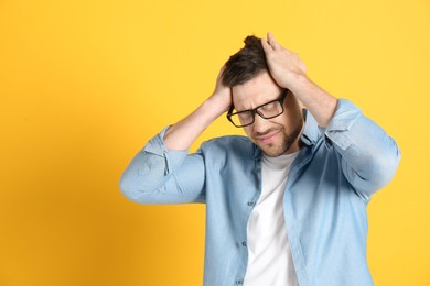 Photo of Man suffering from terrible migraine on yellow background. Space for text