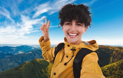 Beautiful young woman taking selfie in mountains