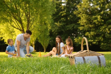 Picnic basket and happy family on background in park