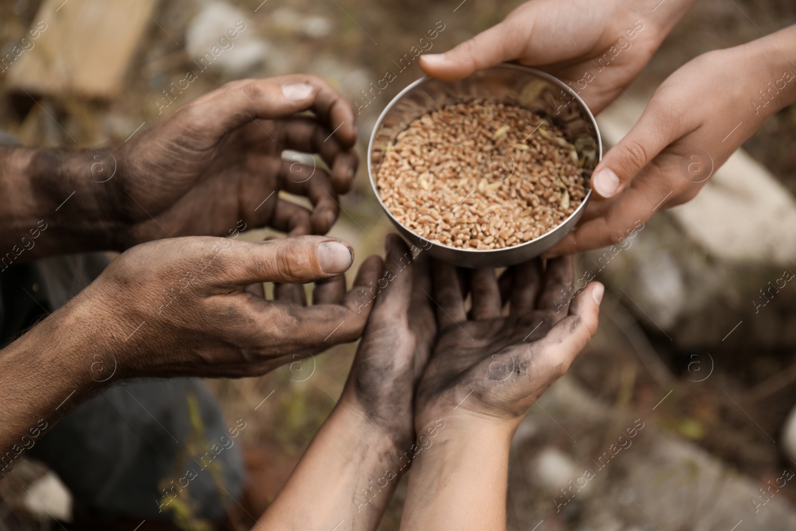 Photo of Woman giving poor homeless people bowl of wheat outdoors, closeup