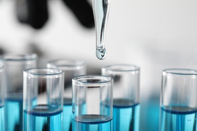 Photo of Dripping liquid from pipette into test tube in laboratory, closeup