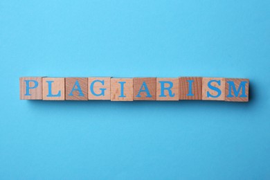 Photo of Word Plagiarism made of wooden cubes with letters on light blue background, top view