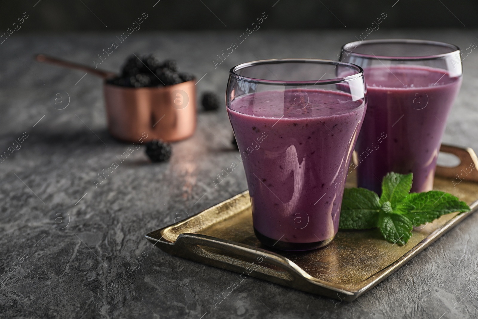 Photo of Glasses with tasty blackberry yogurt smoothies on grey table