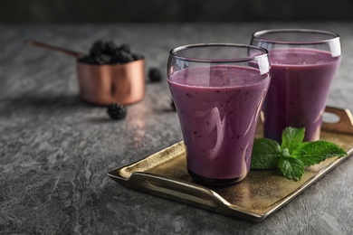 Photo of Glasses with tasty blackberry yogurt smoothies on grey table