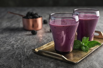 Glasses with tasty blackberry yogurt smoothies on grey table