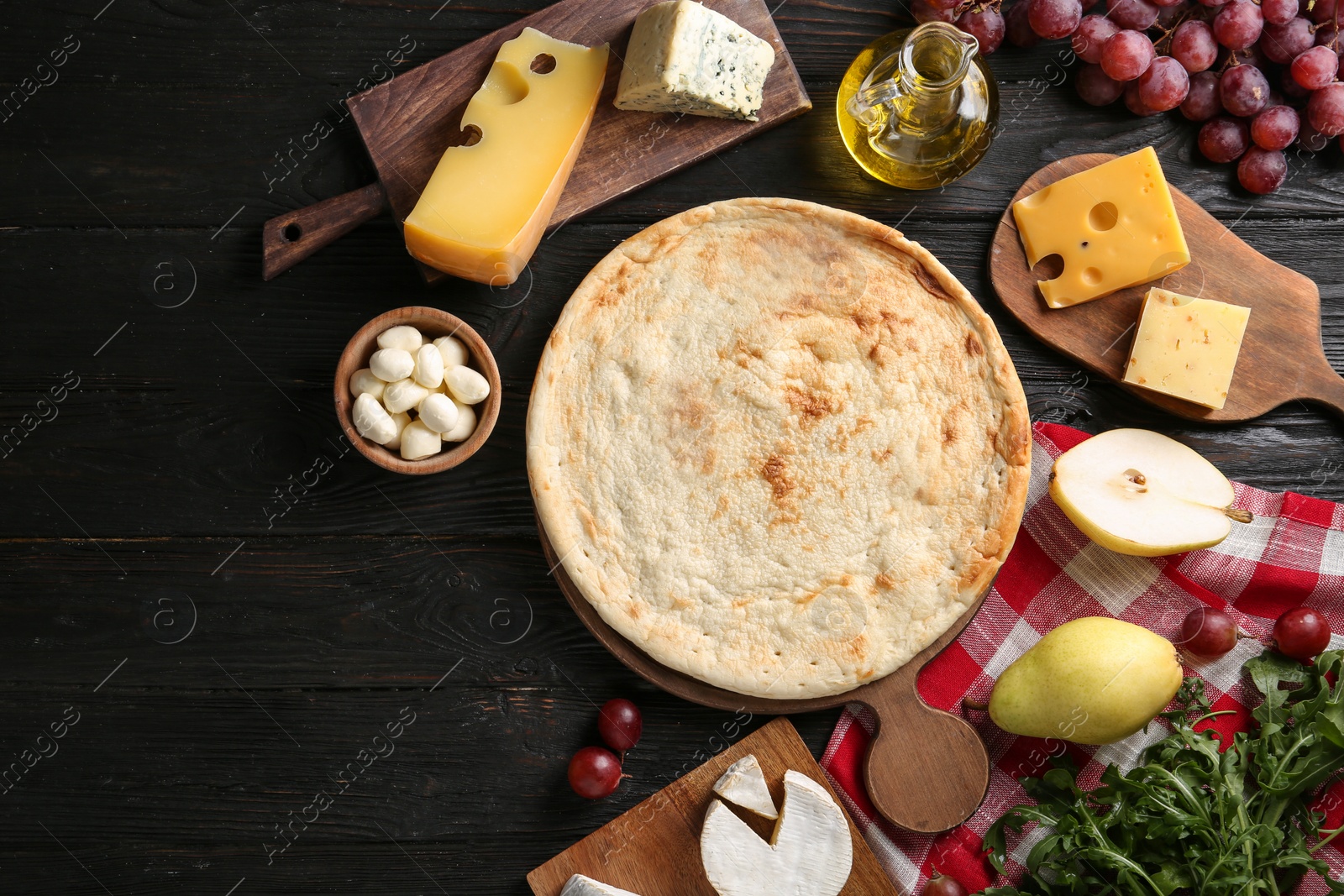 Photo of Flat lay composition with pizza crust and fresh ingredients on black wooden table