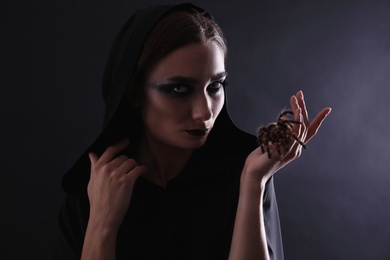 Photo of Mysterious witch with spooky spider on black background