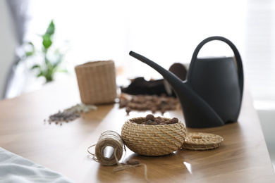 Expanded clay, rope and watering can on wooden table at home. Engaging hobby