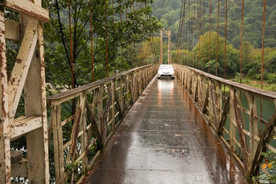 Photo of Beautiful view on rusty metal bridge over river and car in mountains