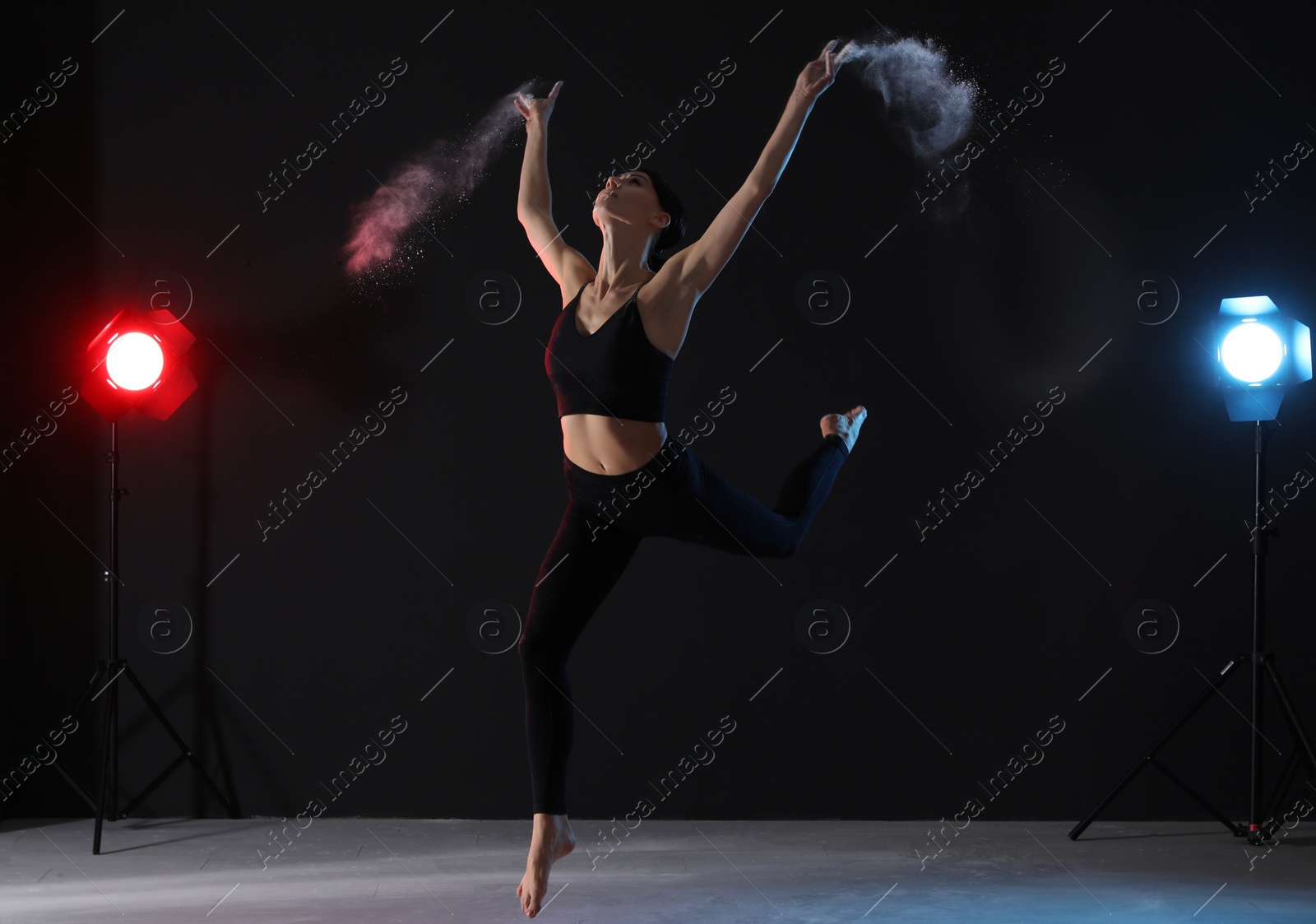 Photo of Professional acrobat with chalk powder exercising in dark studio