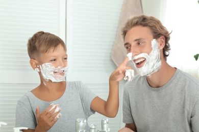 Photo of Father and son applying shaving foam in bathroom