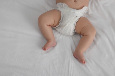 Little baby in diaper lying on bed, top view