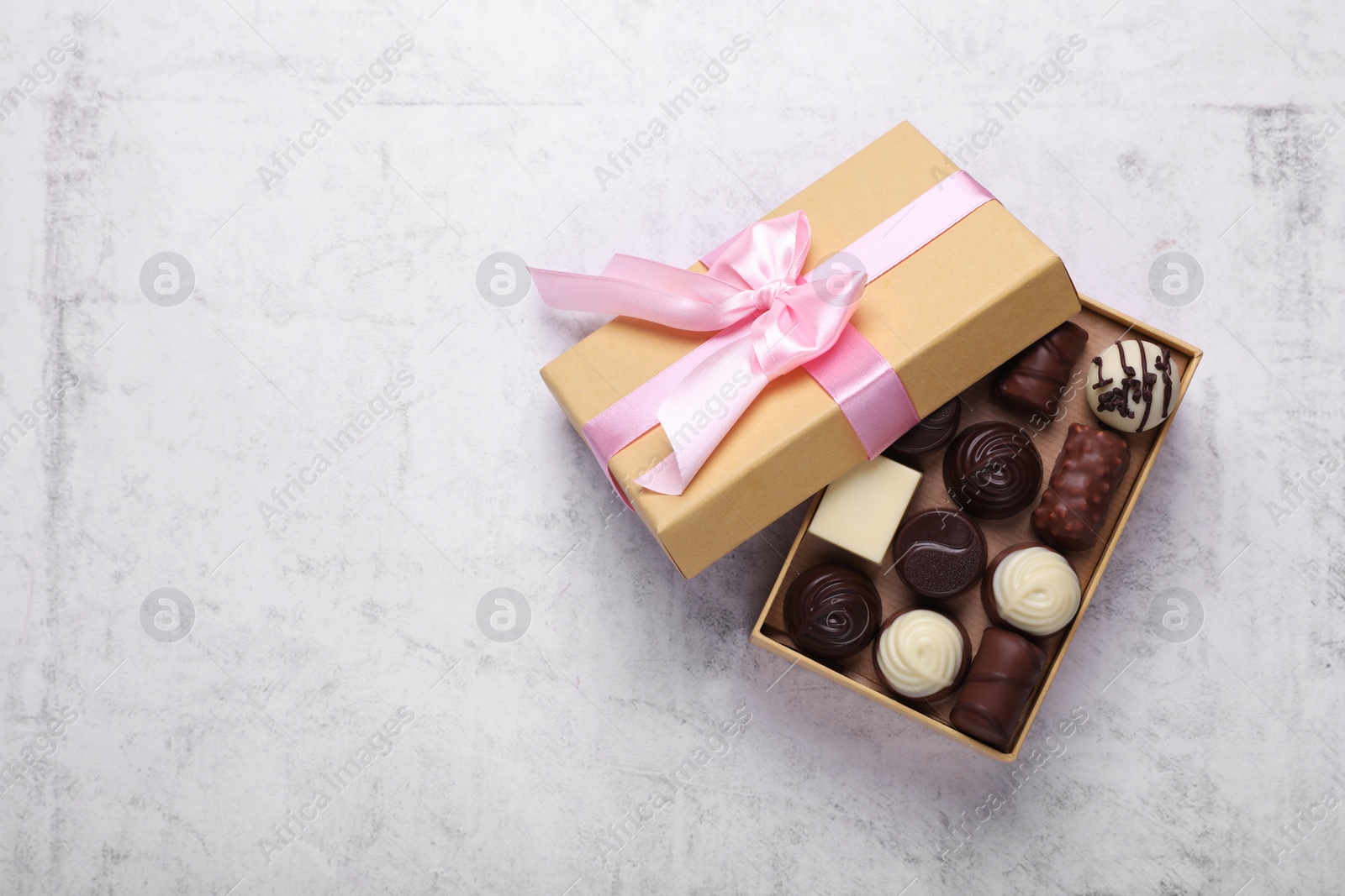 Open box with delicious chocolate candies on white table, top view. Space for text Photo of Open box with delicious chocolate candies on white table, top view. Space for text