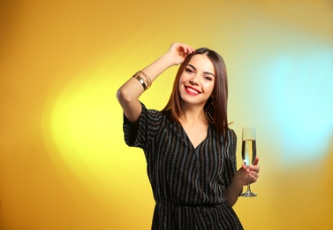 Portrait of happy woman with champagne in glass on color background