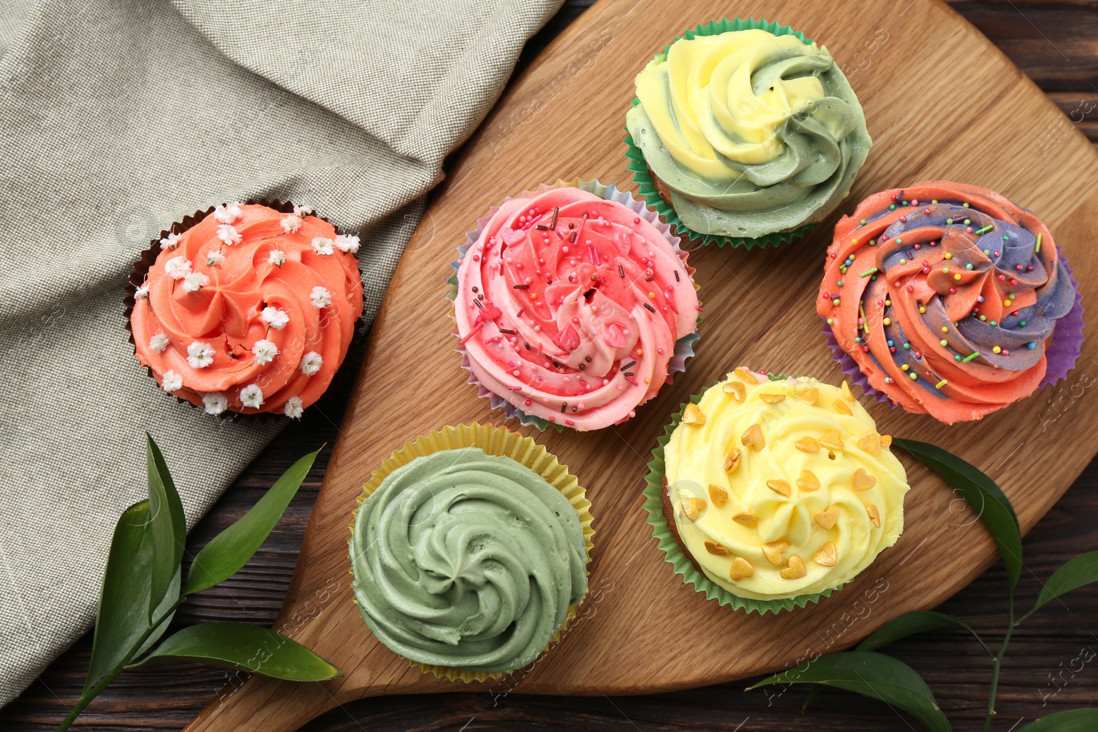 Photo of Delicious cupcake with bright cream on wooden table, flat lay