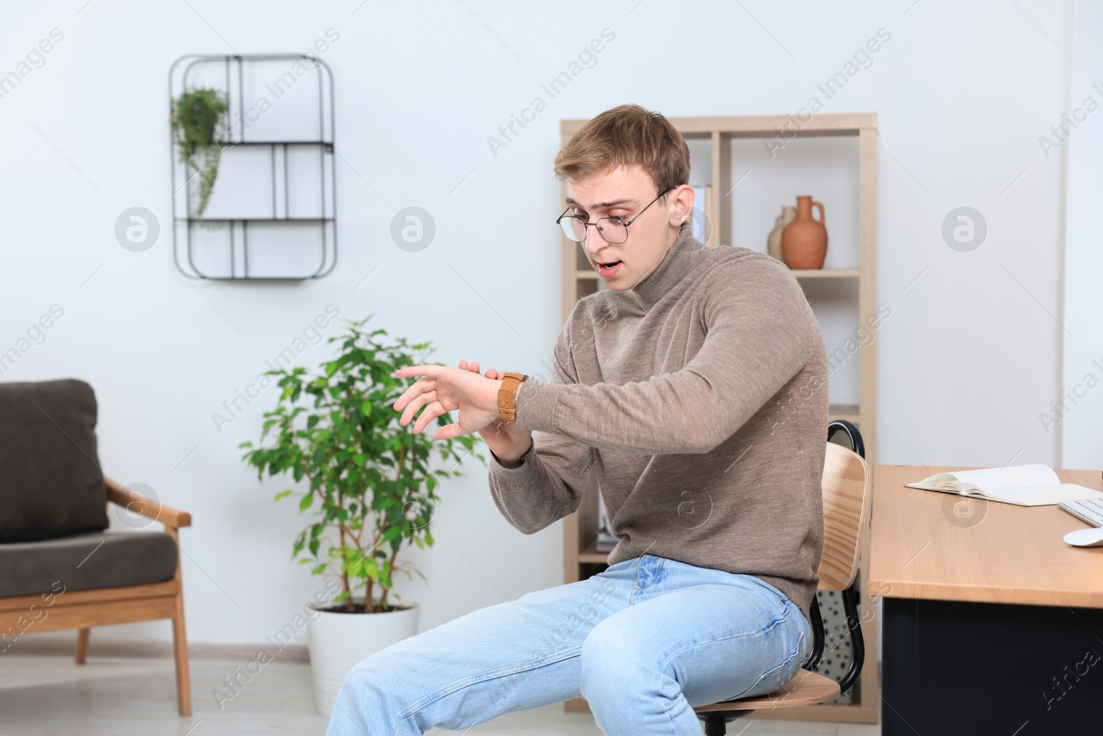 Photo of Emotional young man checking time in office. Being late